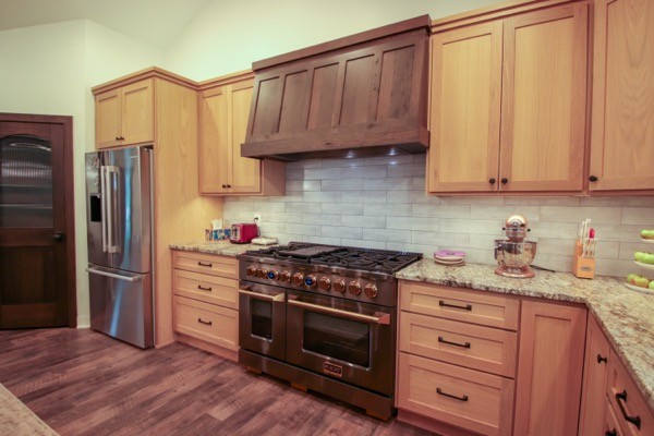 Dark walnut range hood white backsplash light wood cabinets granite countertops