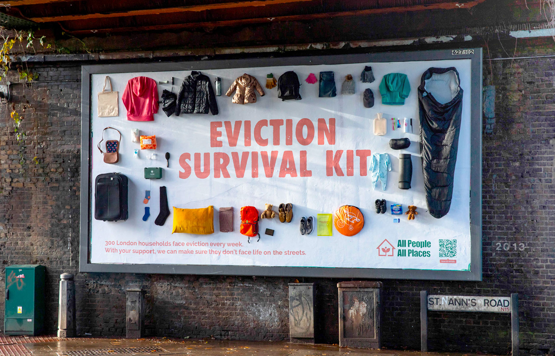 A billboard with real clothes and useful items stuck to it on a wall in London. It reads Evicition Survival Kit