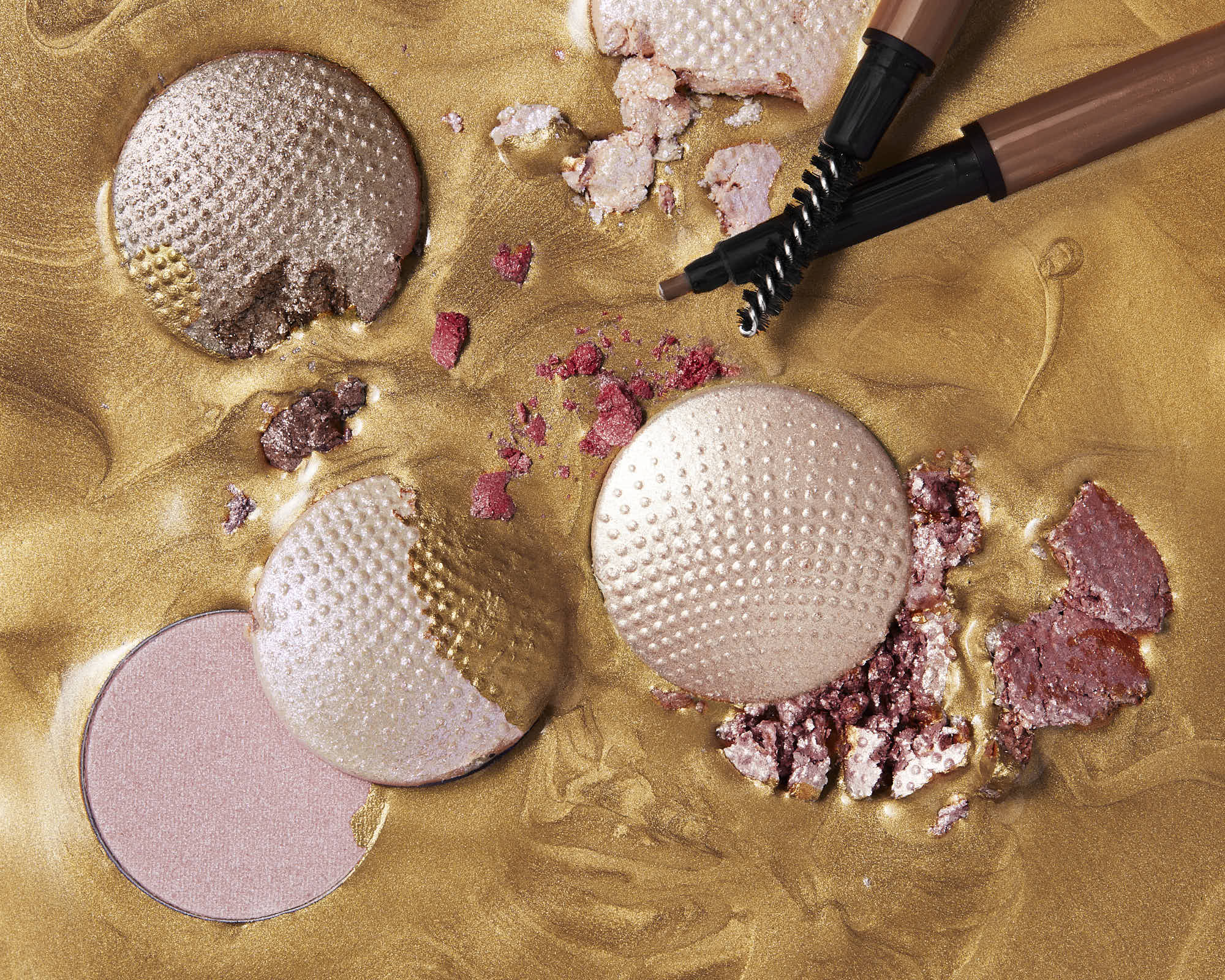 cosmetic powder and compacts crushed in golden paint with cosmetic brushes dipping into fra