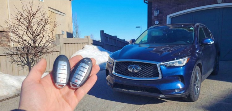 Duplicate Infiniti proximity key fobs with the vehicle parked in a driveway.