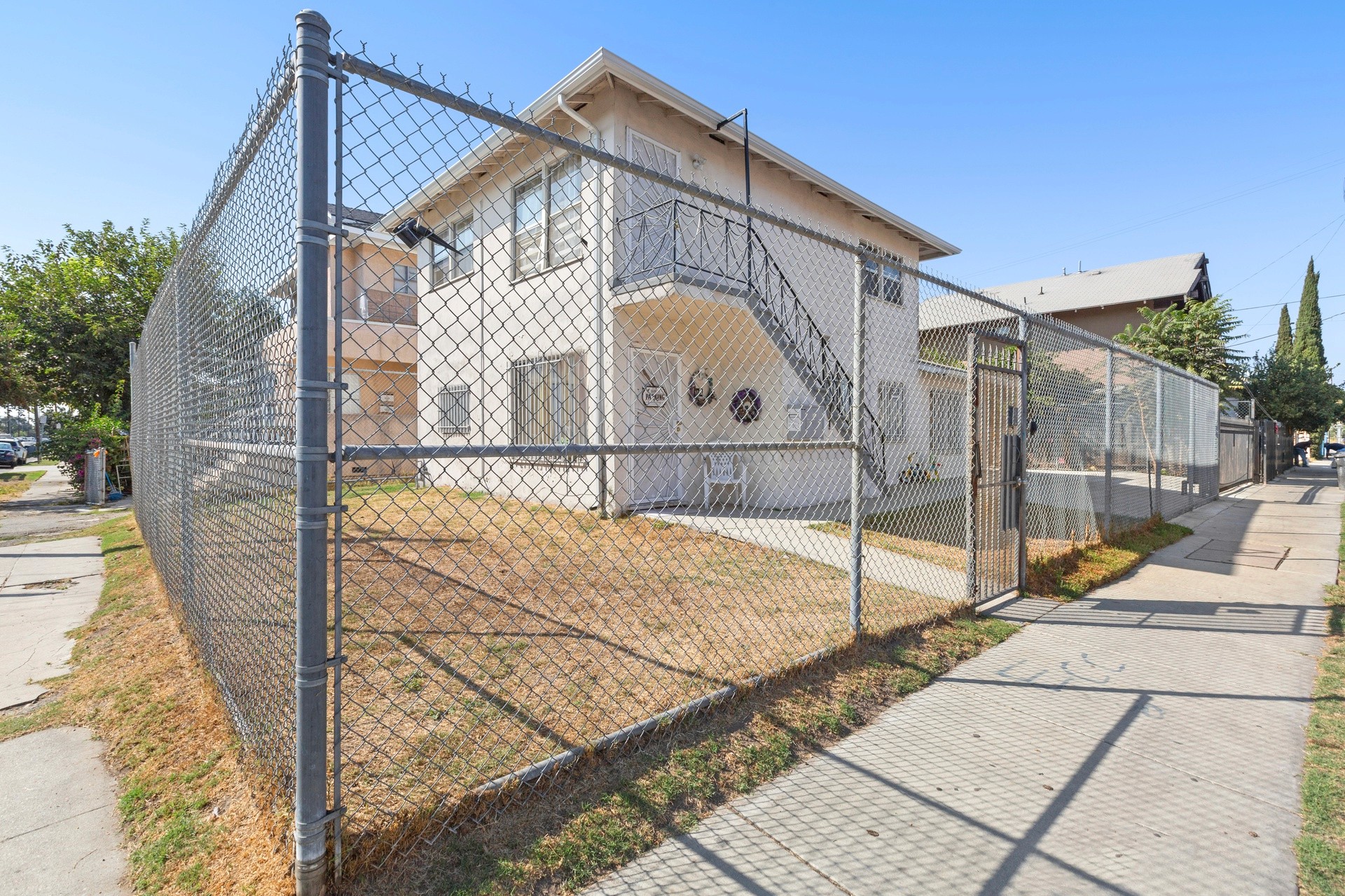 A multifamily site at 4421 Wall, with a fenced area around a two-story building and a clear blue sky above.
