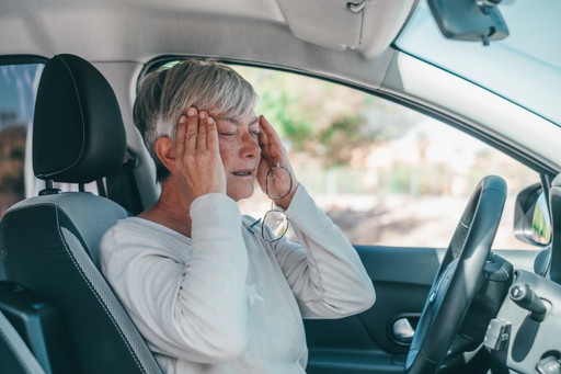mujer en el coche que sufre de dolor de cabeza