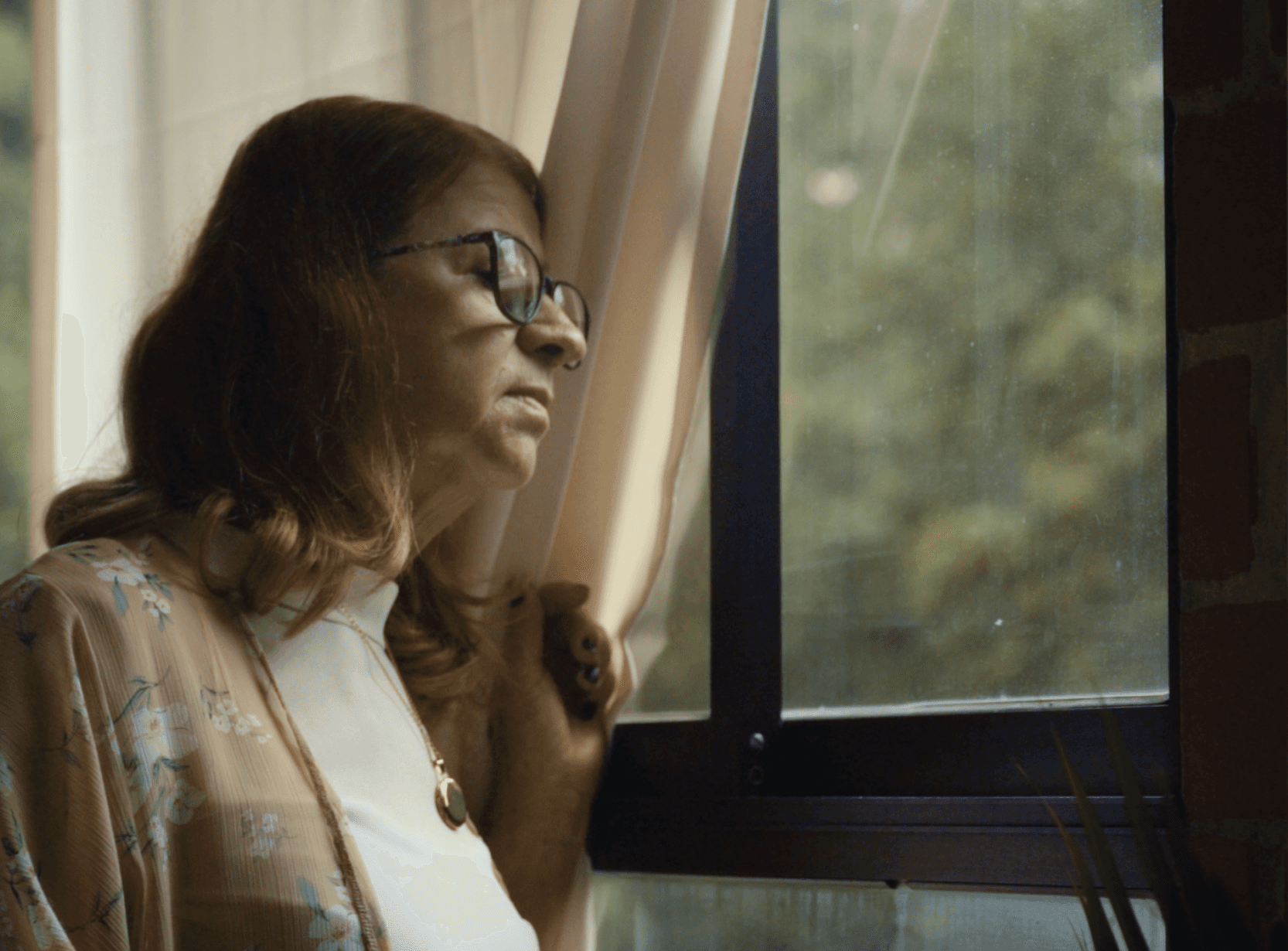 View of the French countryside through a stone villa’s open living room, with sofas and trees framing the scene
