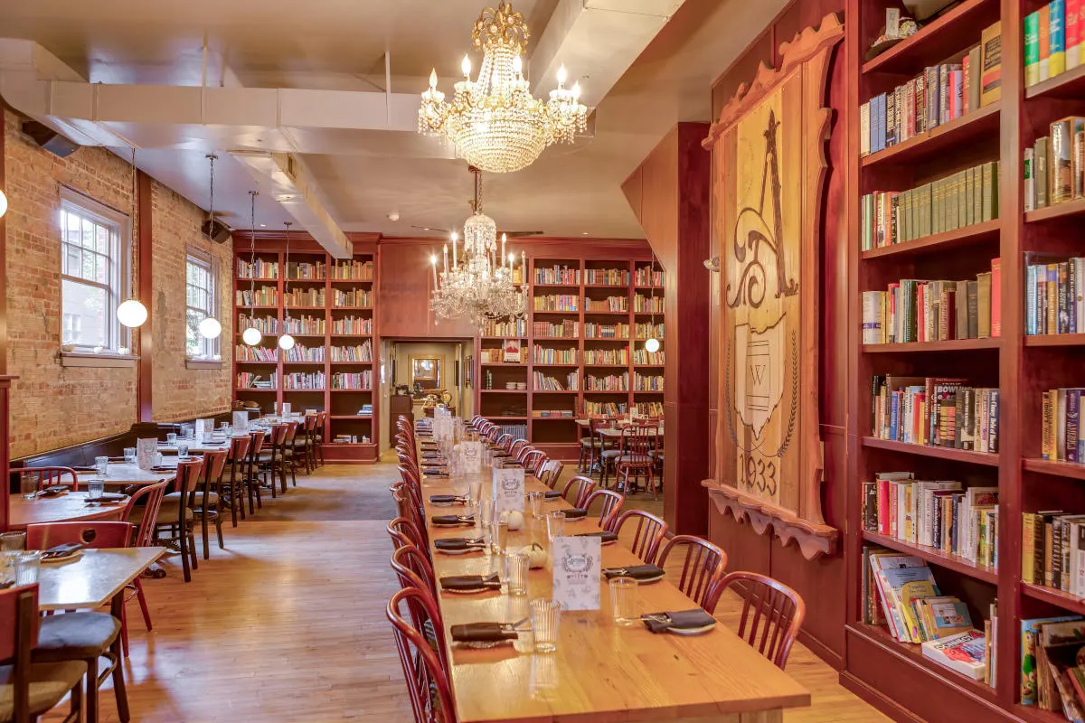 Dining room with chandeliers, brick walls and bookshelves at Asterisk