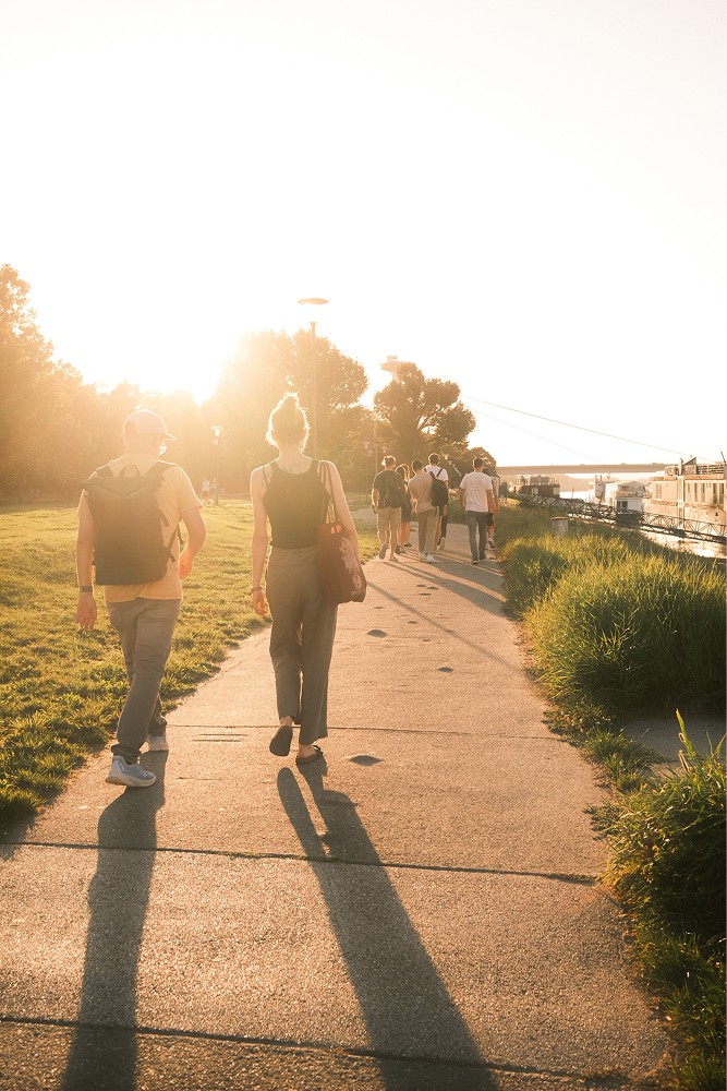 Spaziergang einer Gruppe am Wasser in der Abendsonne.