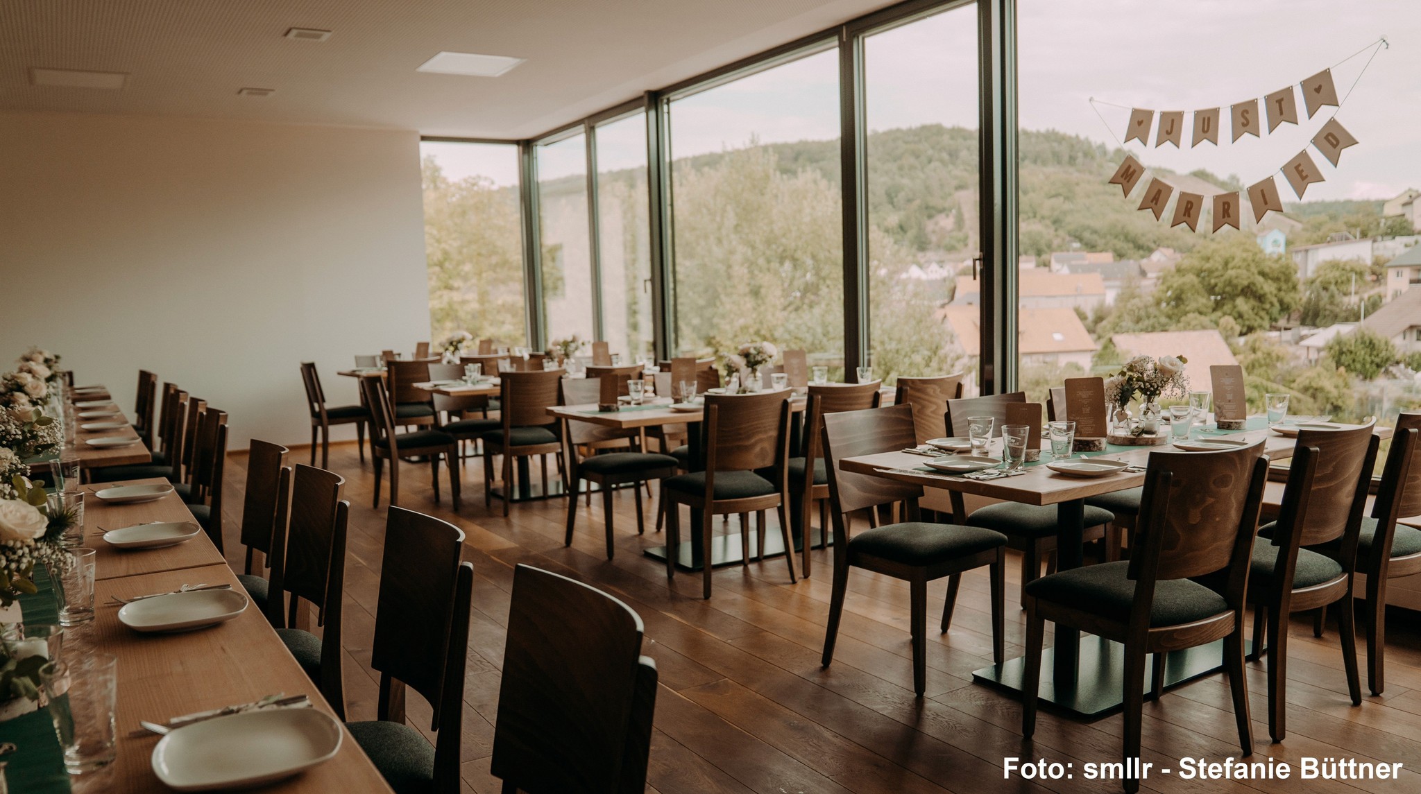 Lichtdurchfluteter Veranstaltungsraum im Weingut Neder mit festlich gedeckten Tischen und großer Panorama-Glasfront