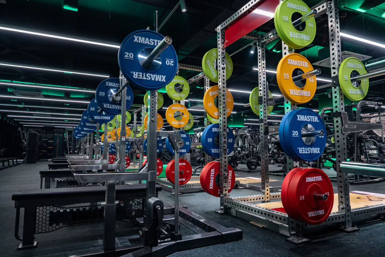 A gym scene featuring several people engaged in various workouts amidst fitness equipment.
