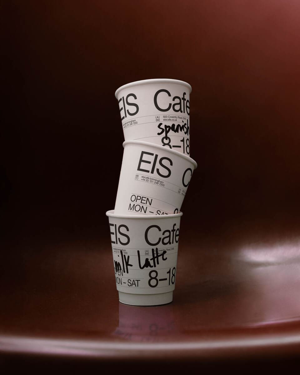A photo of 3 coffee cups stacked one on top of the other against a dark red background.