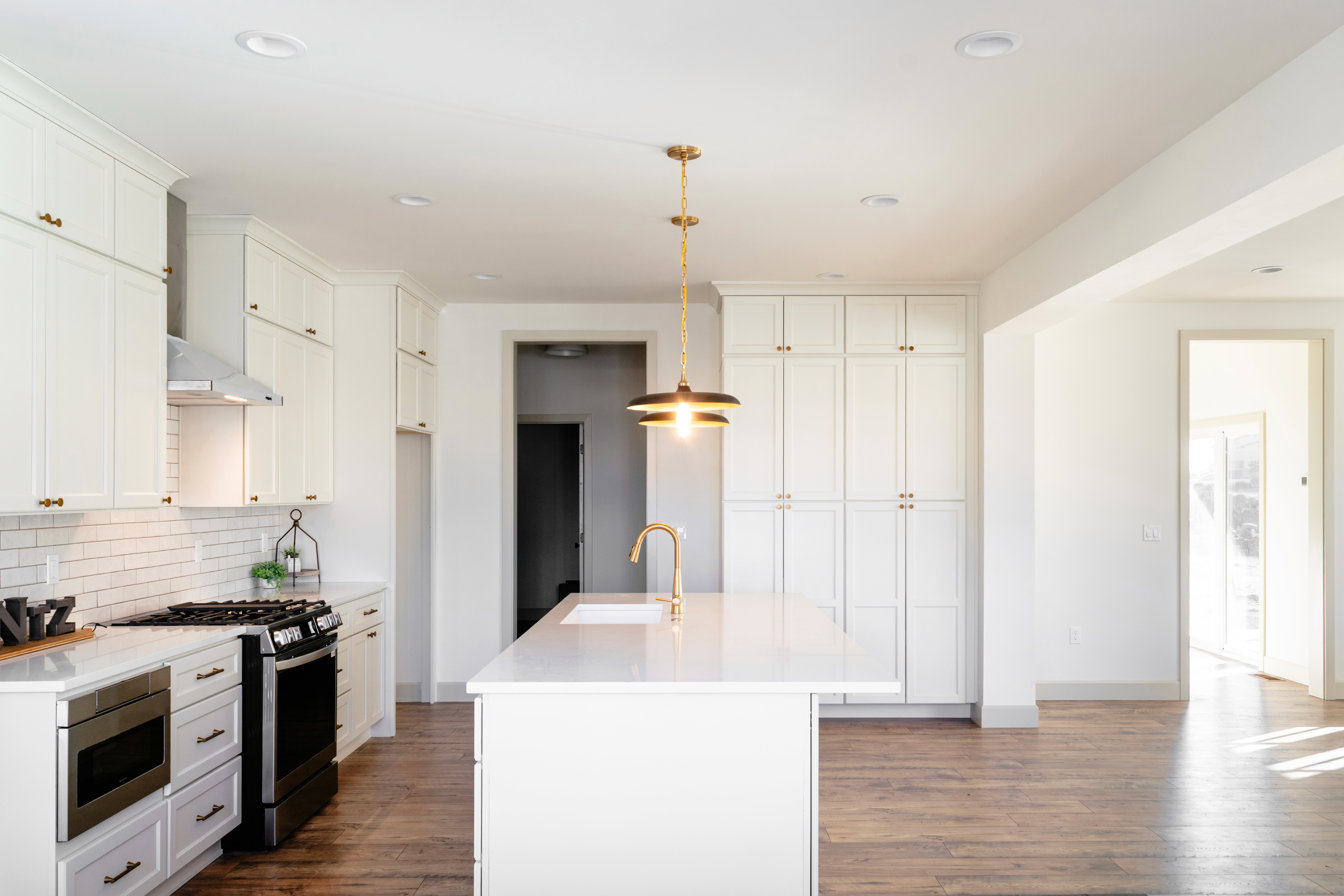 Side view of the kitchen with appliances along the left wall, opens up to the living room to the right.
