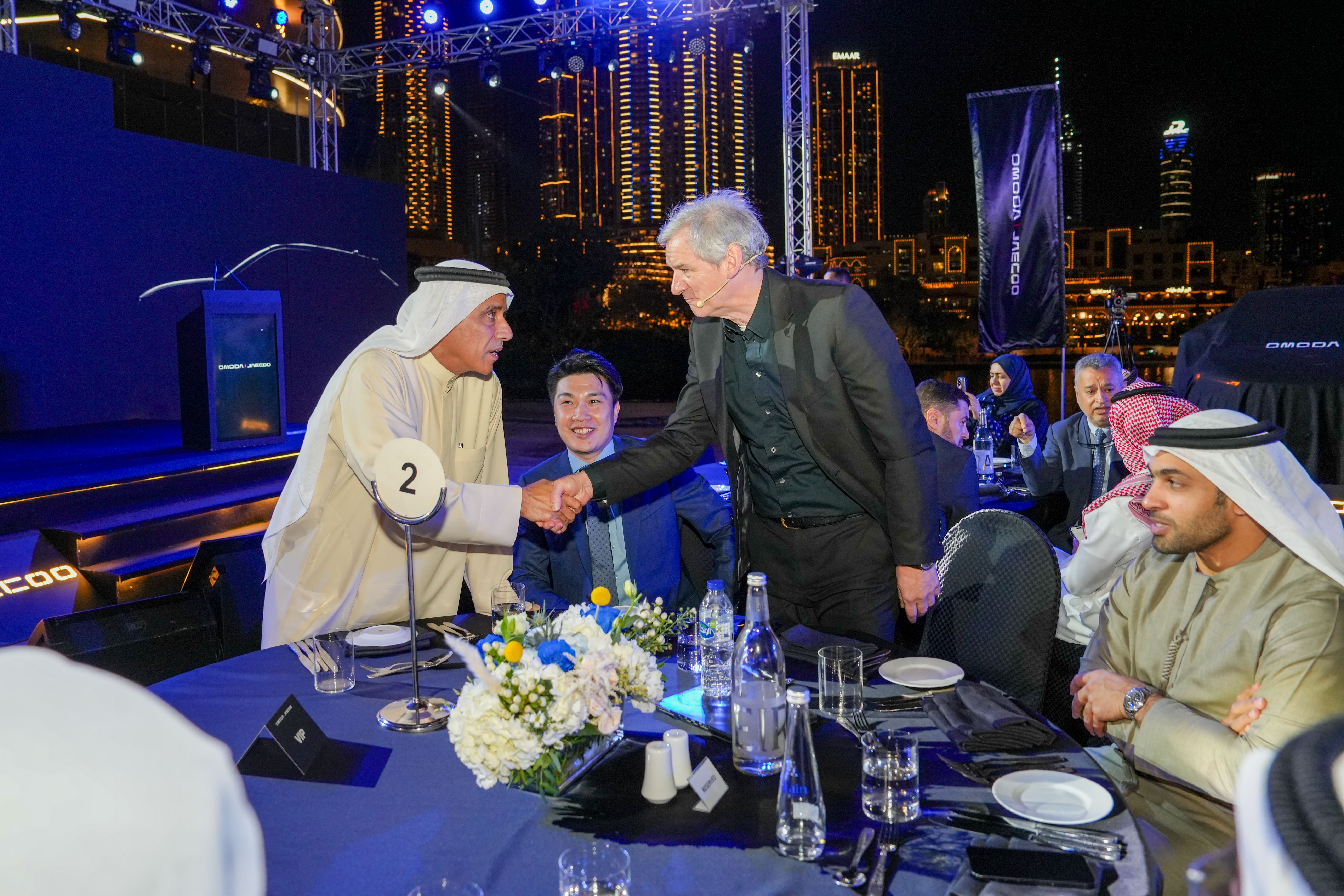 Man in a white shirt focused on a desktop computer displaying charts and data in a softly lit workspace.