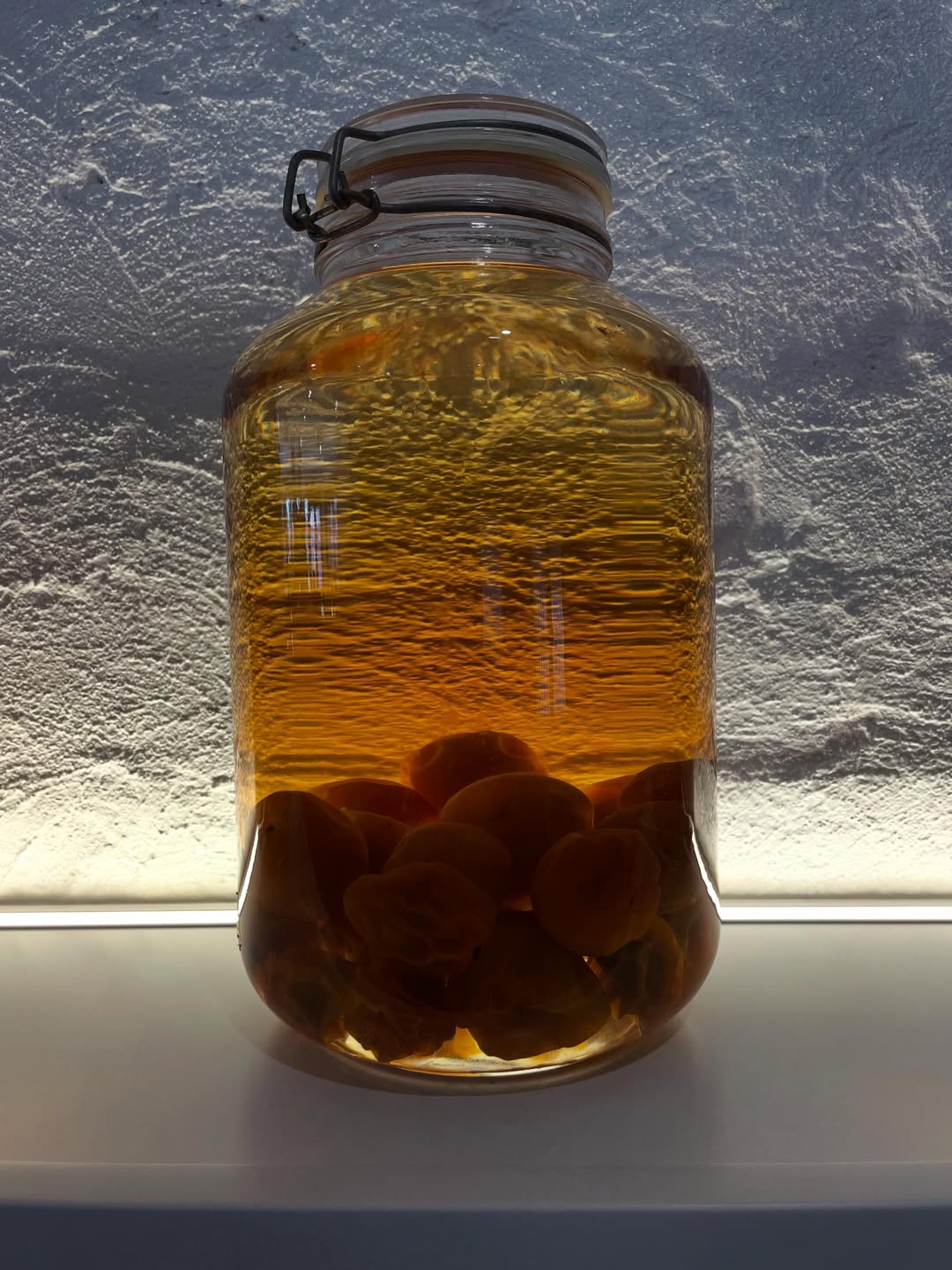 Wooden outdoor table set with multiple plates of food, including dips, salads, potatoes with cheese, and glasses of water, with hands reaching in to eat.