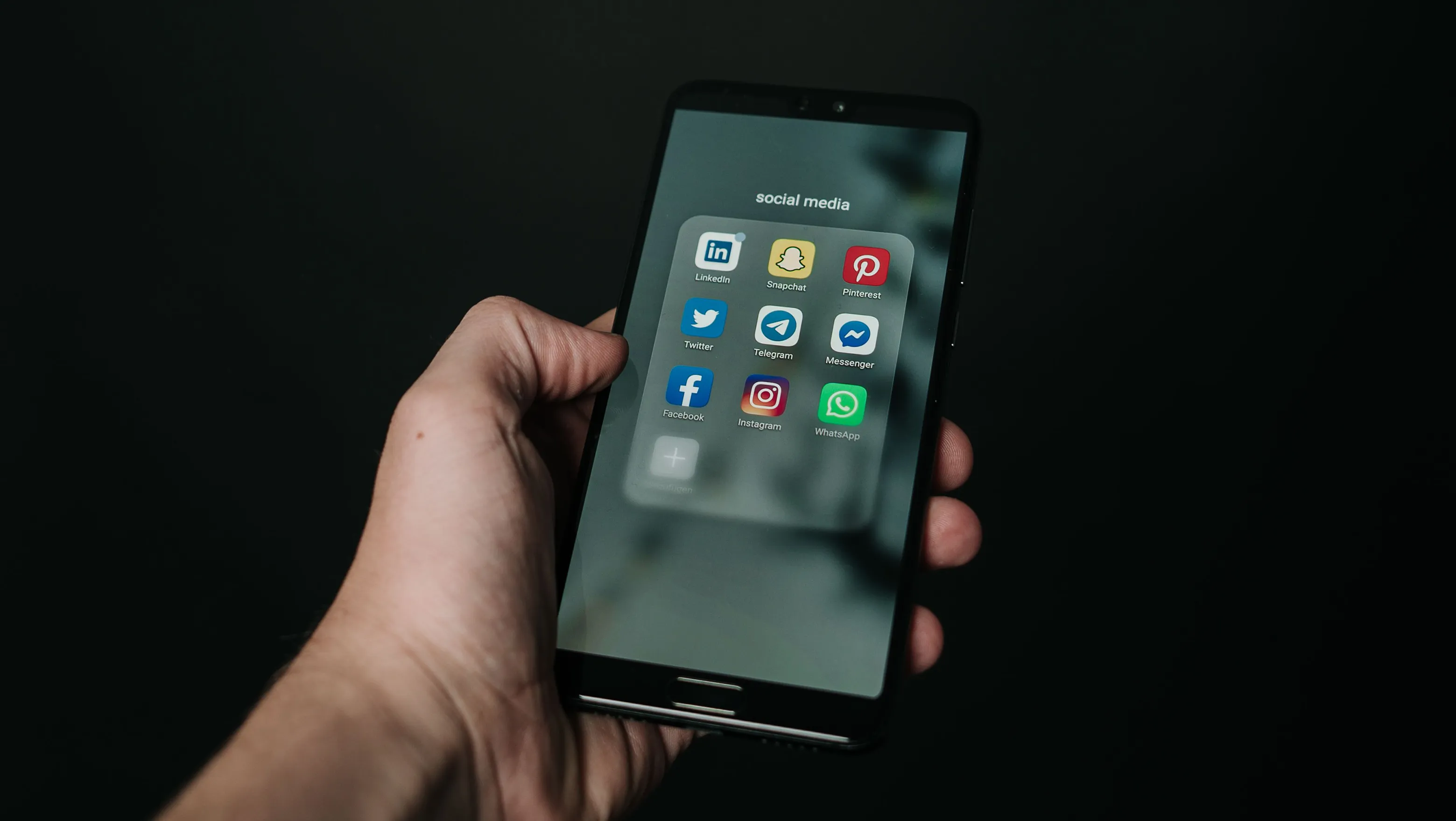 Mano de persona sosteniendo su telefono abriendo aplicaciones de redes sociales.