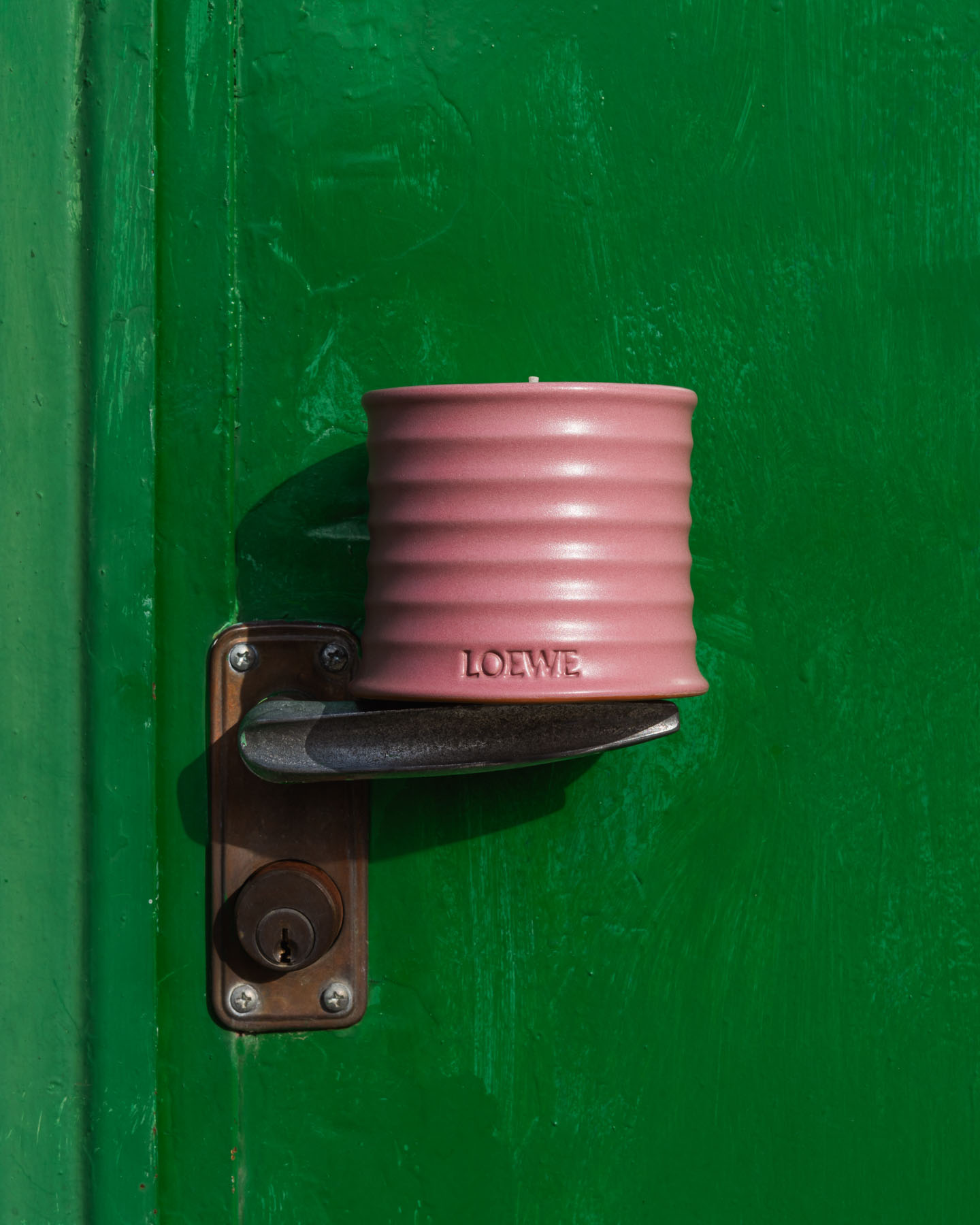 Ivy LOEWE Home Scents candle displayed against a vivid green painted wall.