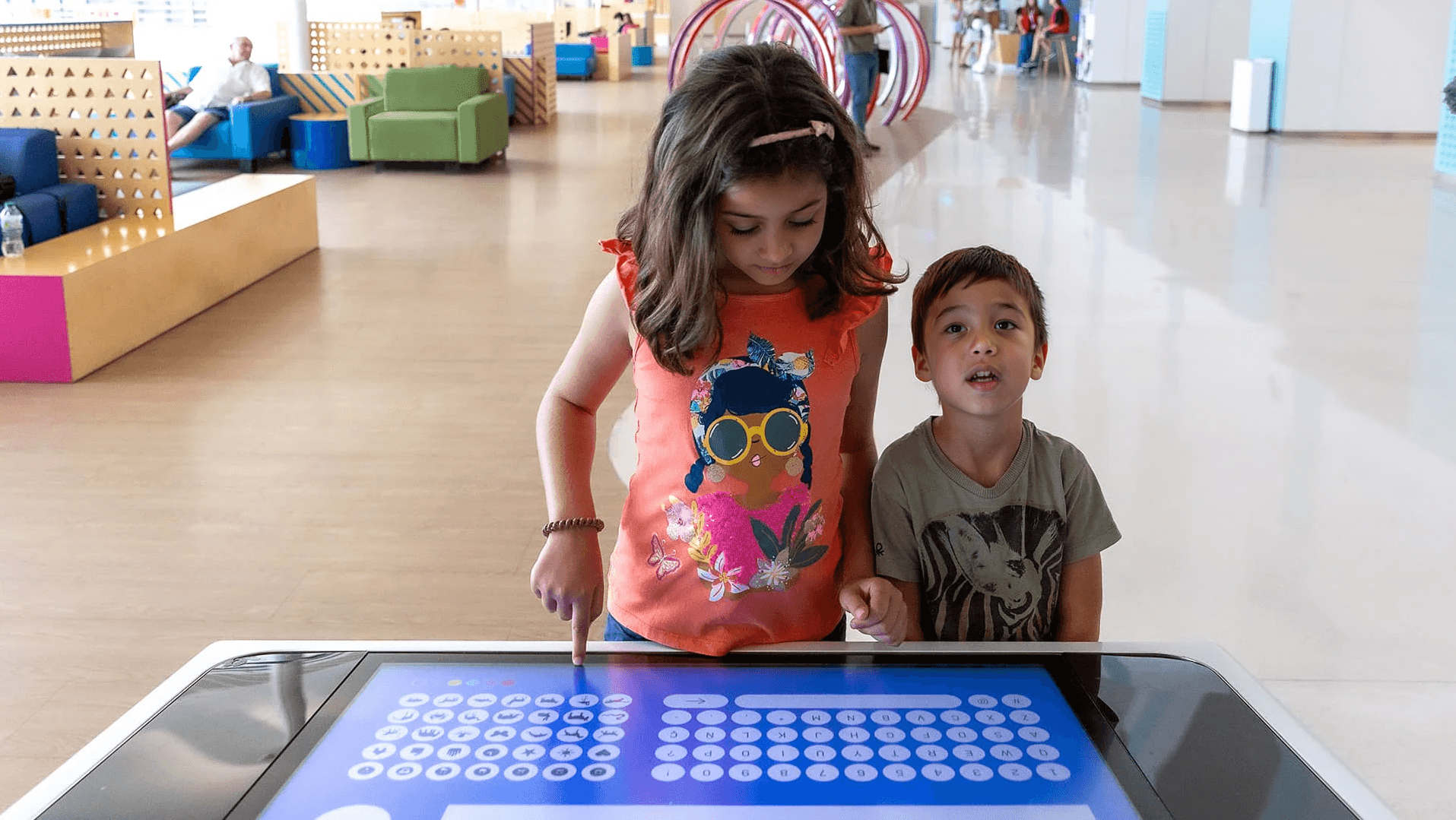 Two children interacting with a large touchscreen installation in the renovated hospital paediatric area