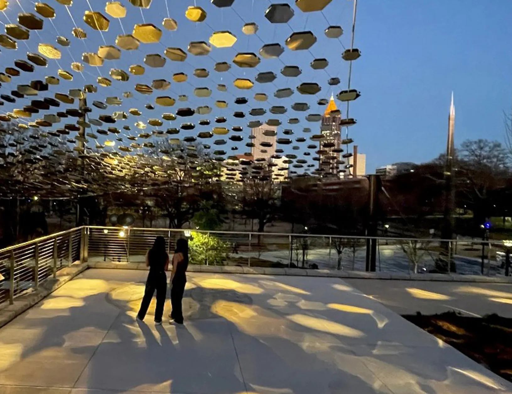 arial view of full metallic hexagon canopy extents with pedestrian view of direct lighting reflections at pavement