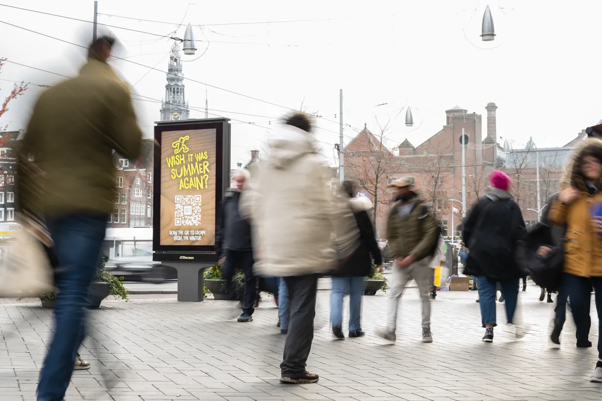 a man walking down a street past a large poster