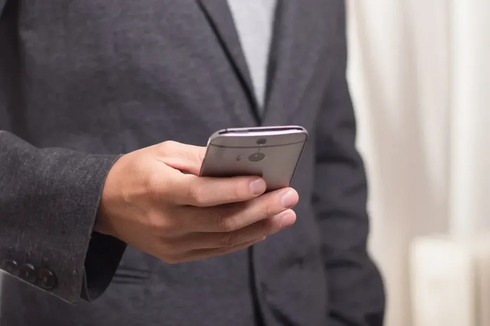 Person im Anzug hält ein Smartphone steht für professionelle Kommunikation und mobile Anwendungen mit mercury.ai