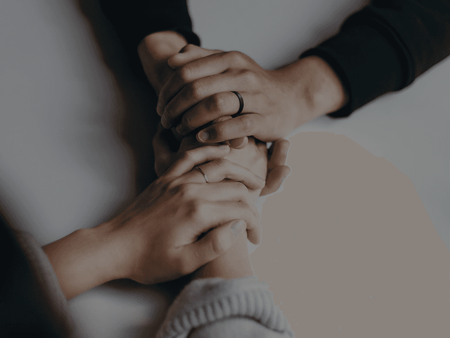 Two hands gently holding each other in a supportive gesture.