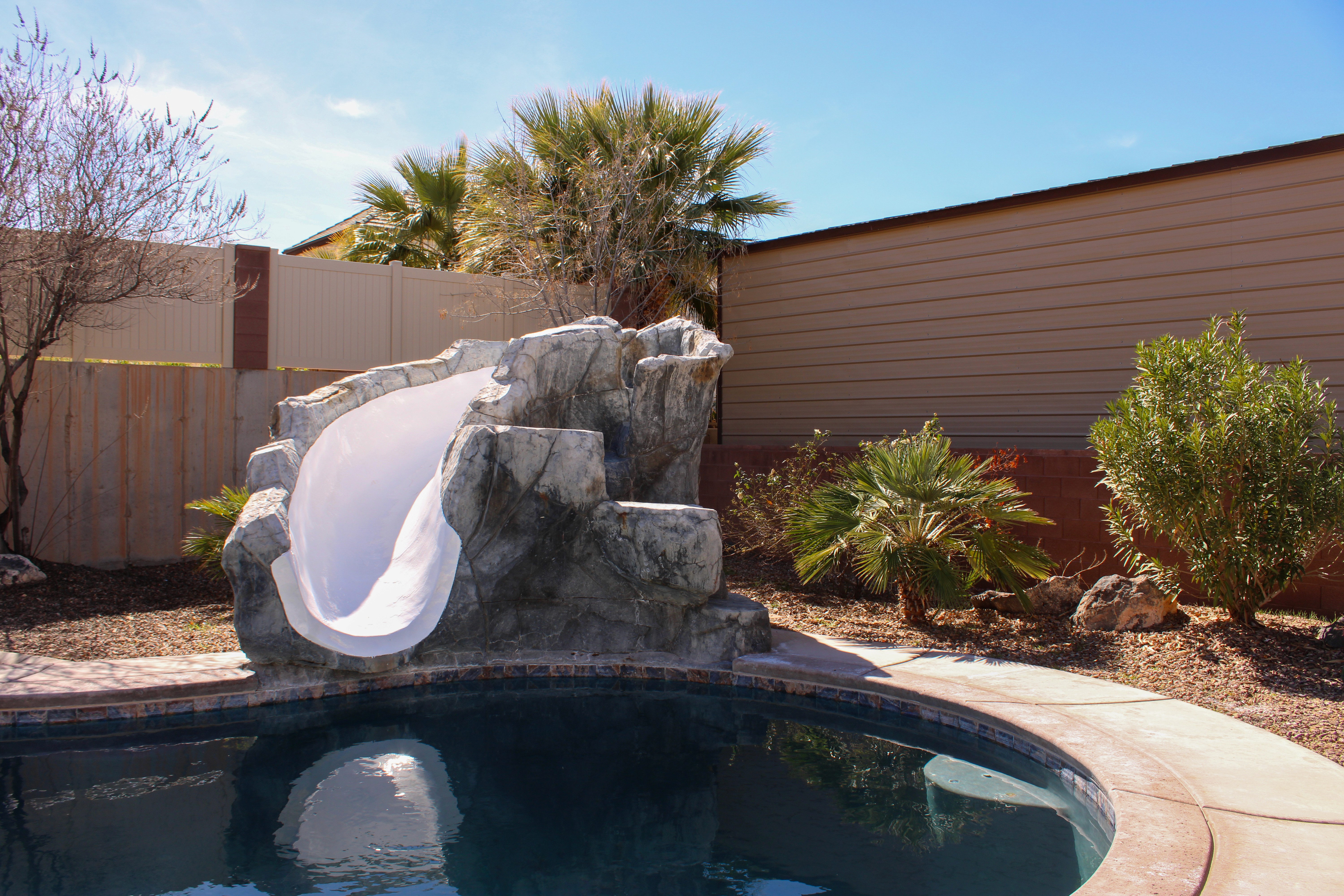 Custom backyard in Washington, Utah featuring a pool with a slide and outdoor entertaining space