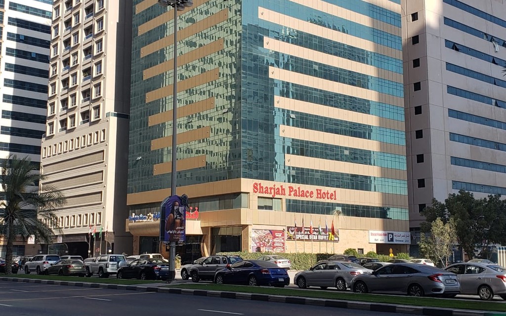 A large mosque with two towers stands in front of tall buildings, located in Al Taawun.