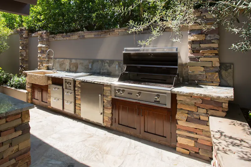 Outdoor kitchen with covered grill and custom cabinets from the Big Canyon Remodel project. Photo by Chris Darnall.