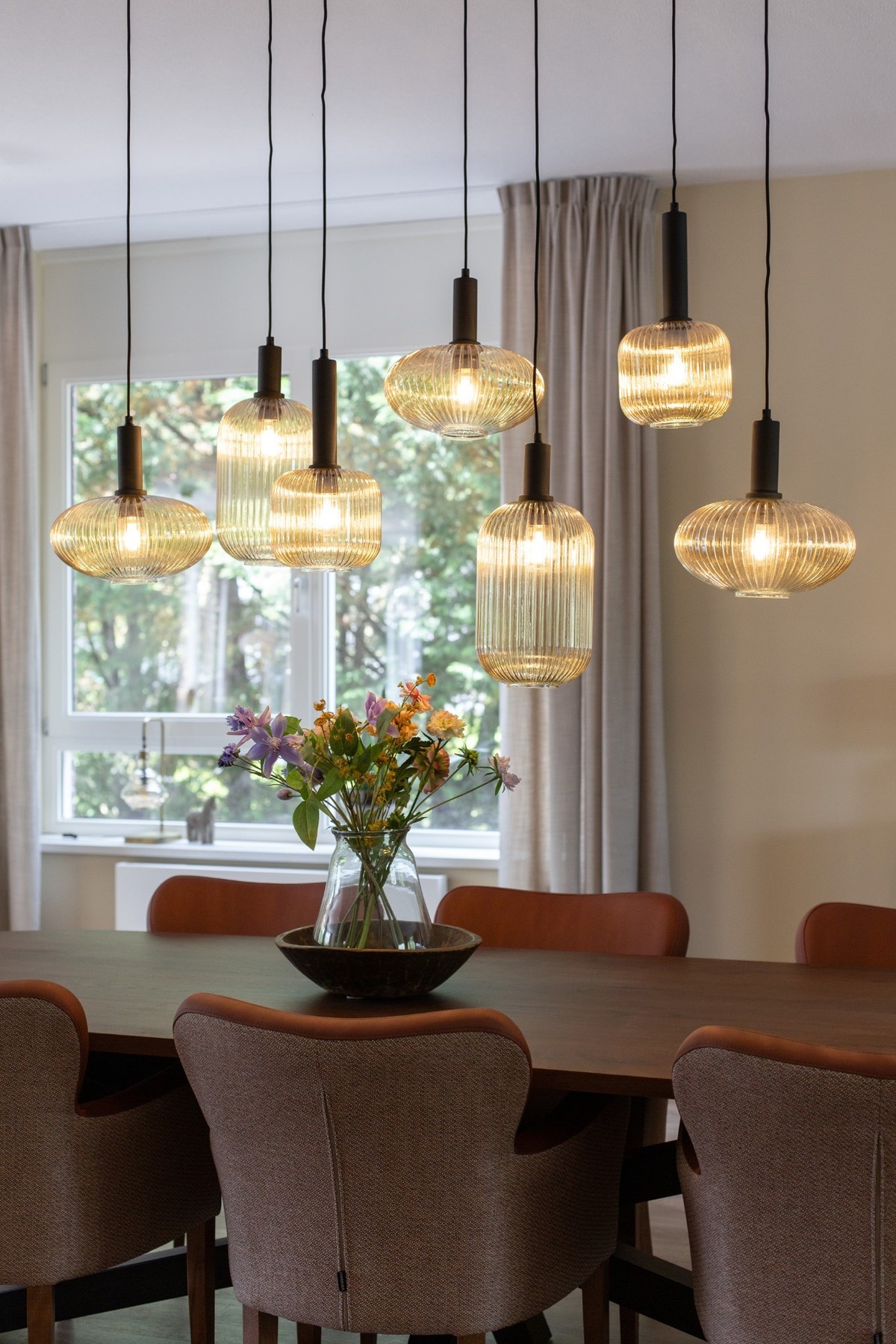 eettafel met terracotta stoelen en groep glaslampen