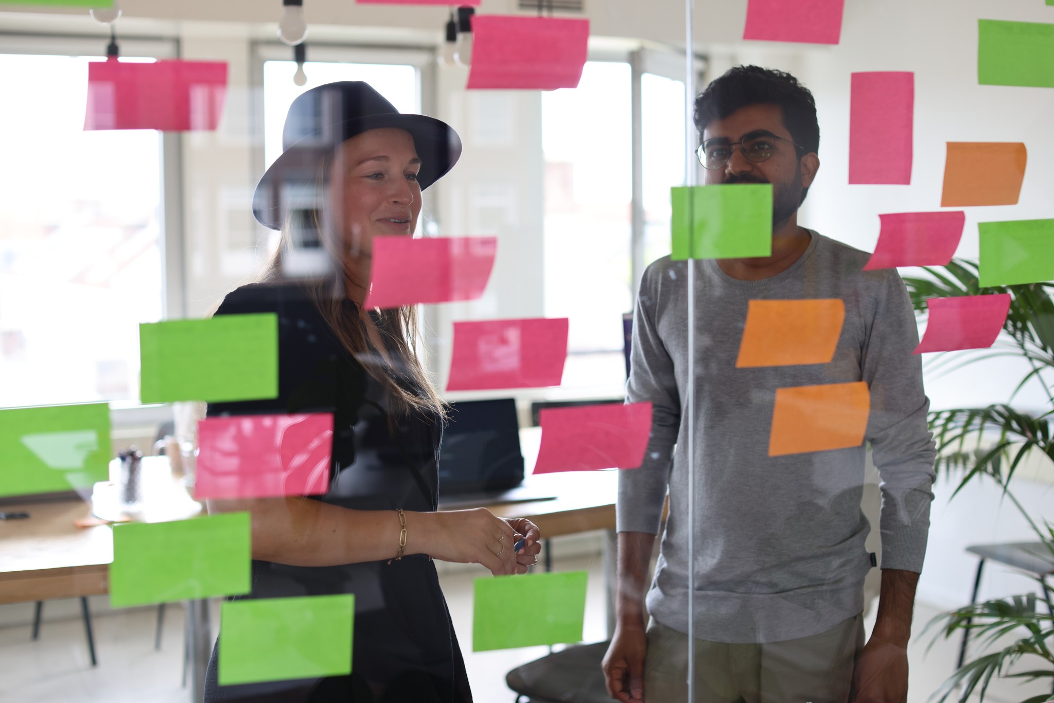 Two people seen through glass with colorful sticky notes on it.
