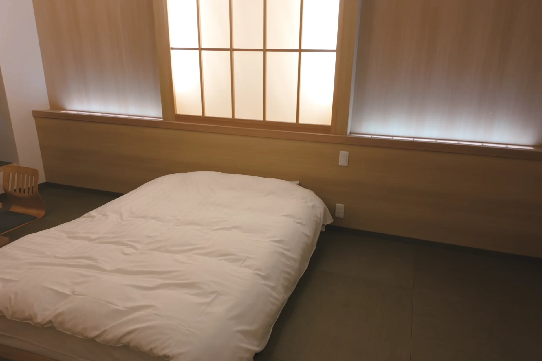 A single futon laid on tatami in a plain Kinosaki guest room lit by a shoji window.