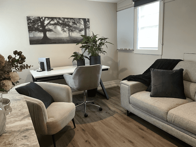 A vacant room with wooden flooring, a sloped ceiling, and a window letting in natural light.