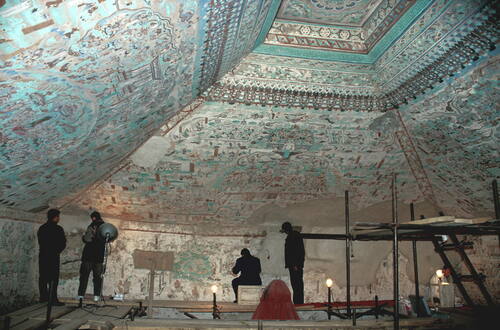 Mogao Caves: Conservation team working inside a decorated cave chamber with richly painted ceilings and walls at the Buddhist rock‑cut sanctuary near Dunhuang, Gansu Province, China