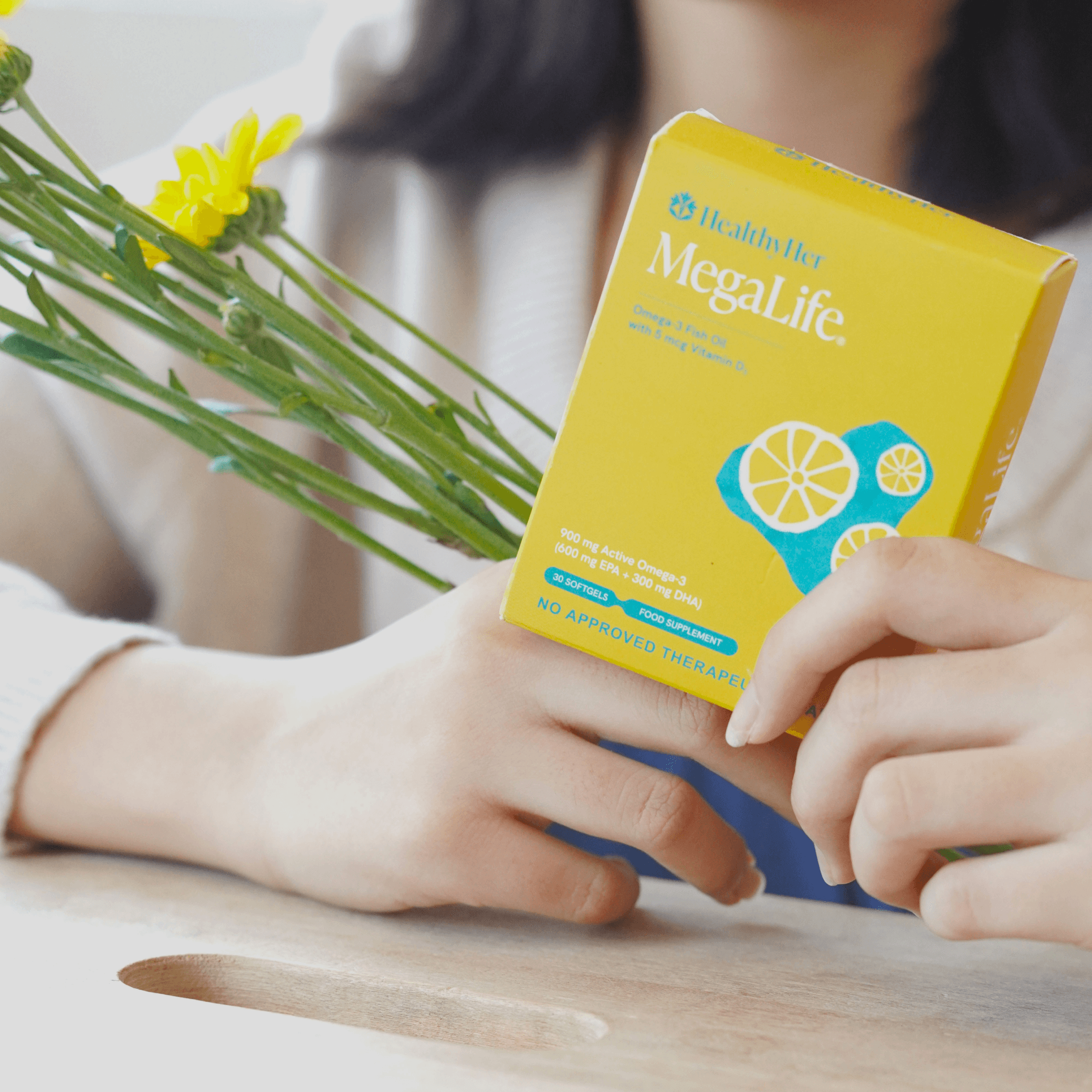 Closeup shot of a woman holding a box of MegaLife soft gels from HealthyHer