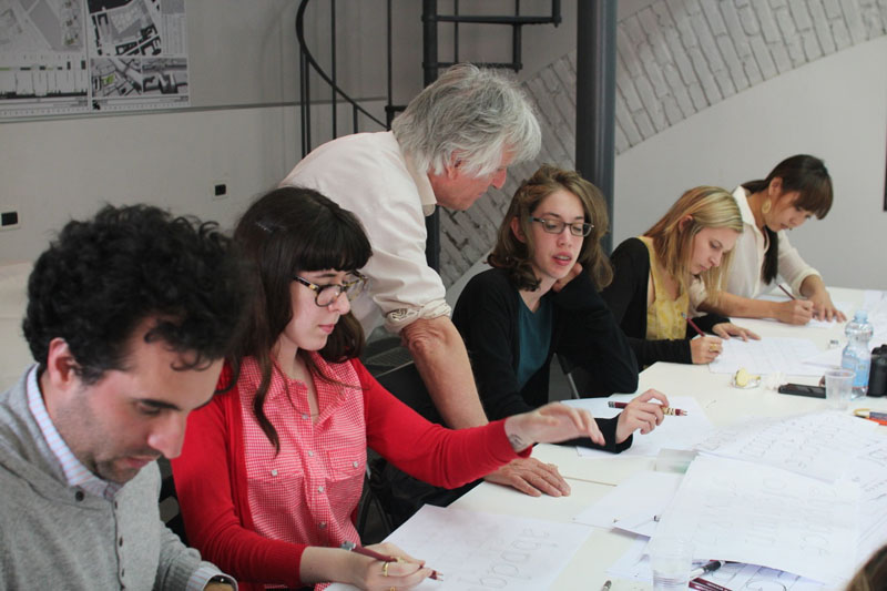 A photo of a teacher talking to the students while they draw different typographical letters.