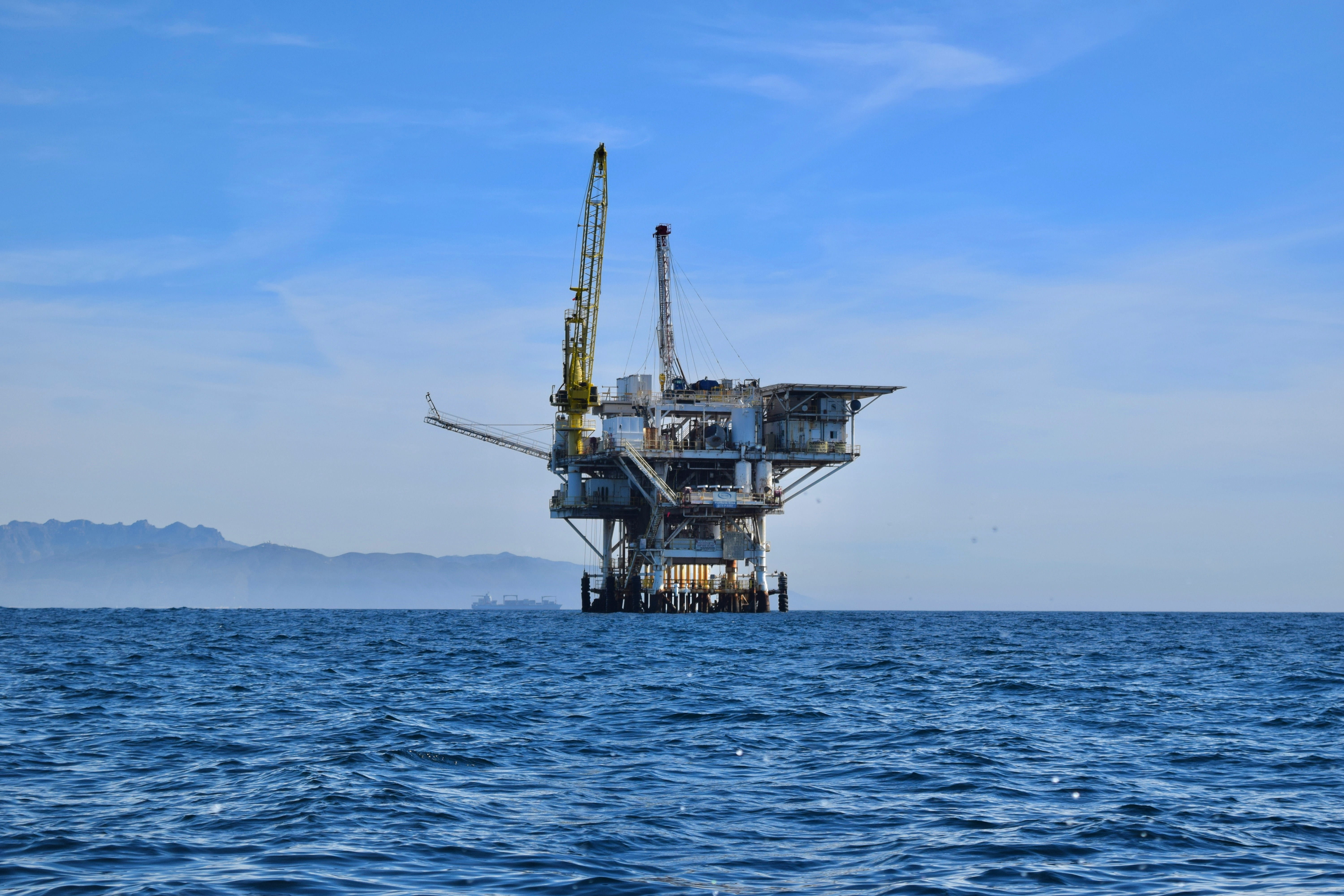 An offshore semi-submersible drilling rig anchored in calm blue waters under a clear sky.