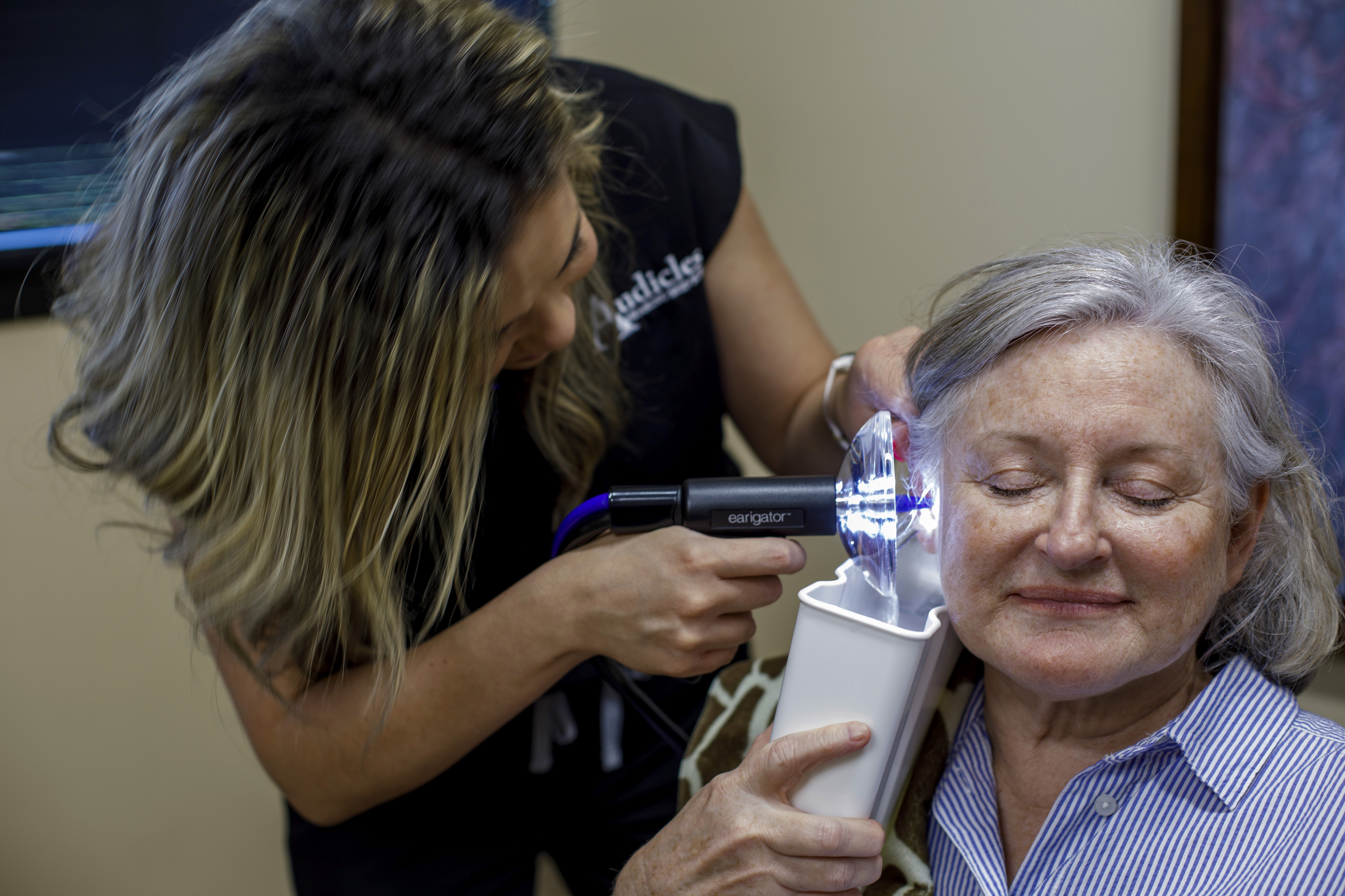 An older woman having earwax removed using an Earigator device