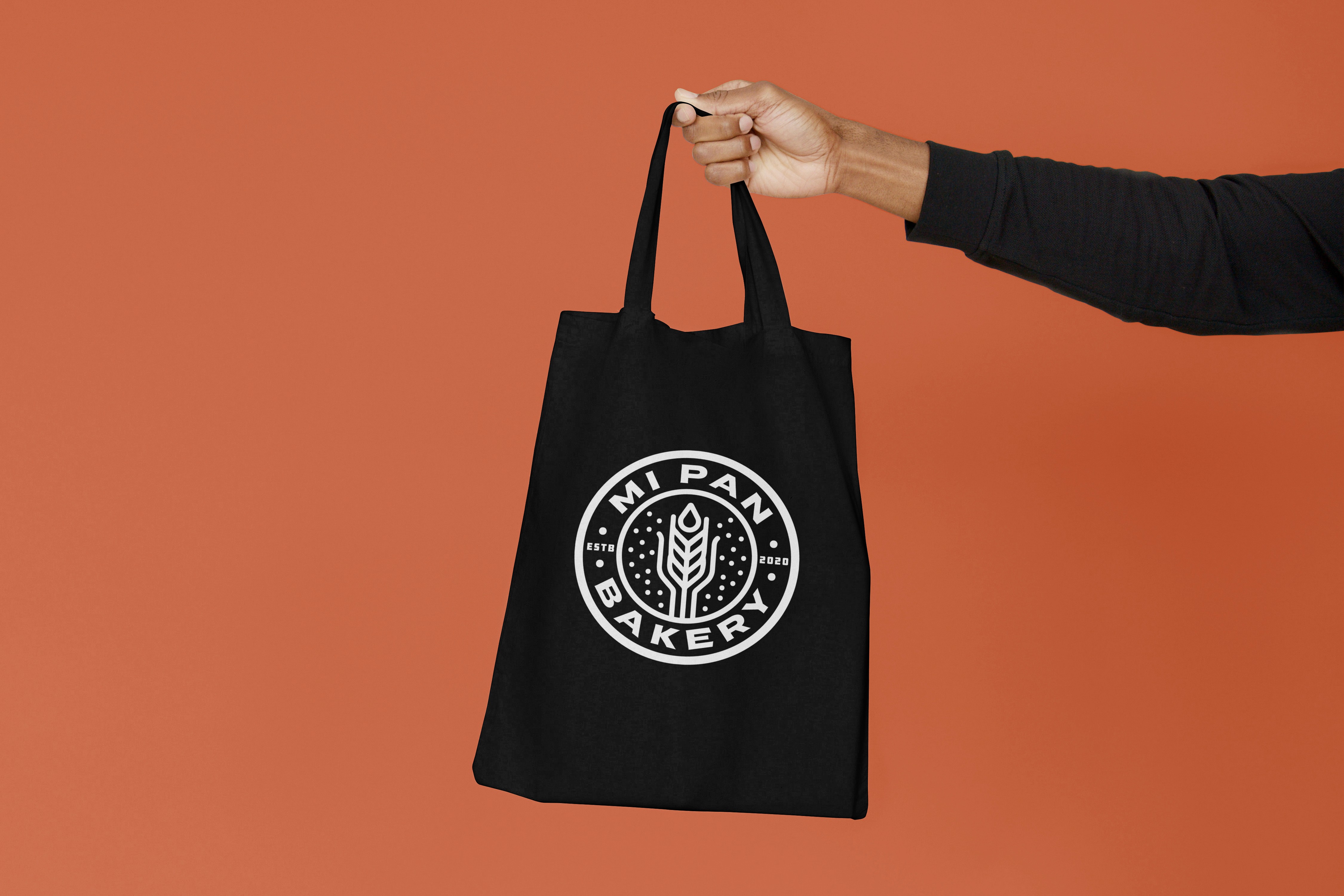 Hand holding Mi Pan Bakery black tote bag with logo