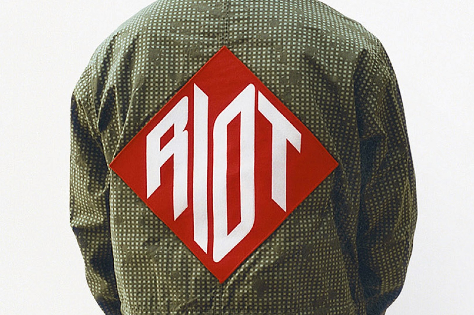 A close-up of two sealed bags containing t-shirts with a Supreme logo on one, and a graphic reading 'RIOT' on the other.