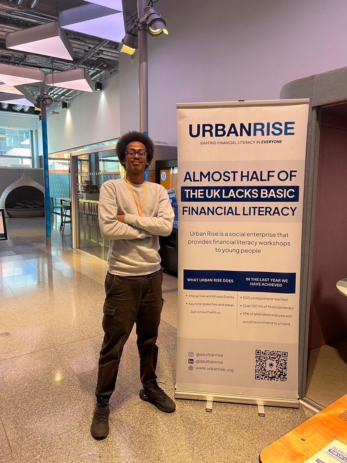 Man standing next to Urban Rise white and blue roller banner. 