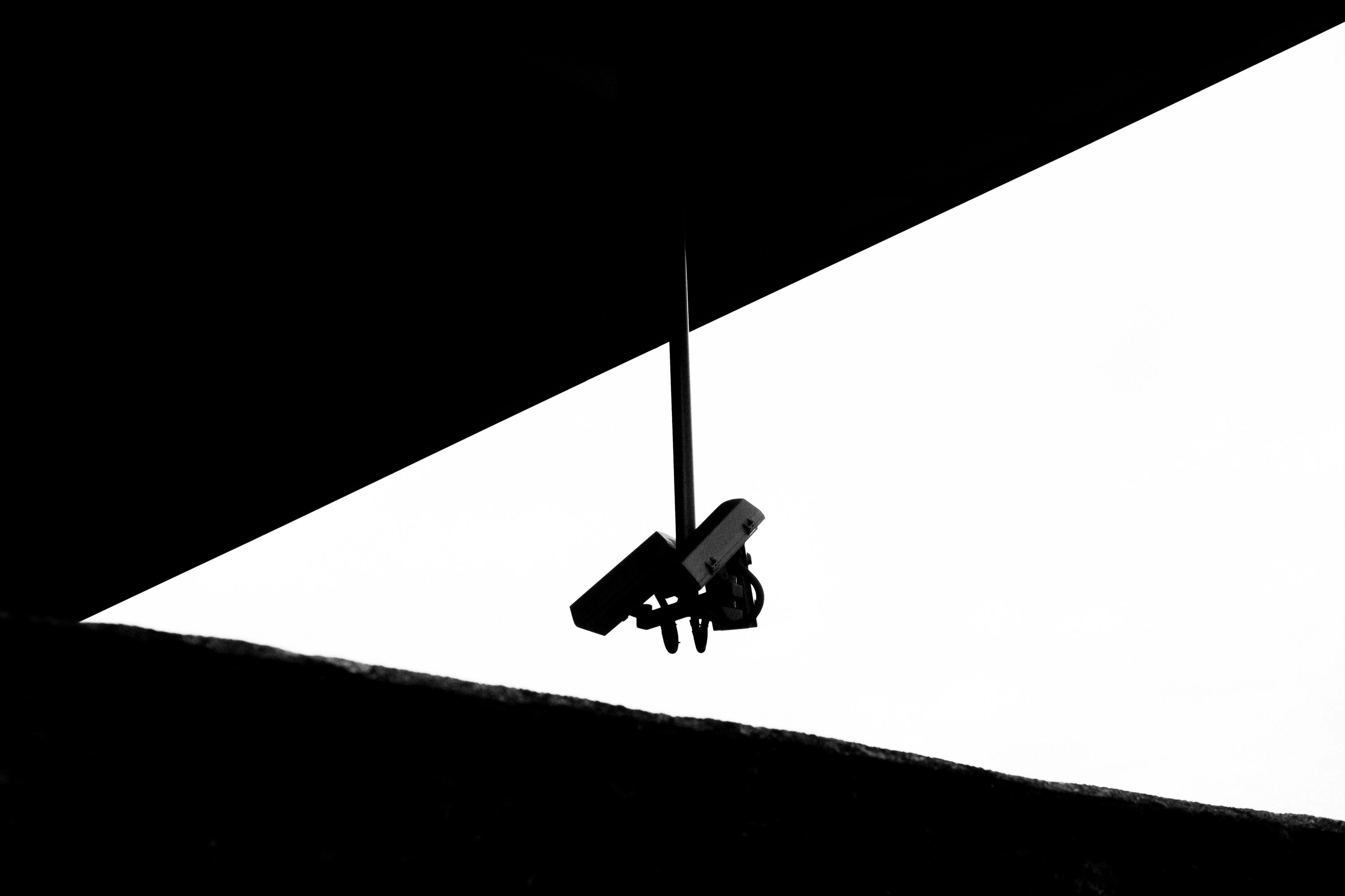 a black and white photo of CCTV cameras hanging from a ceiling