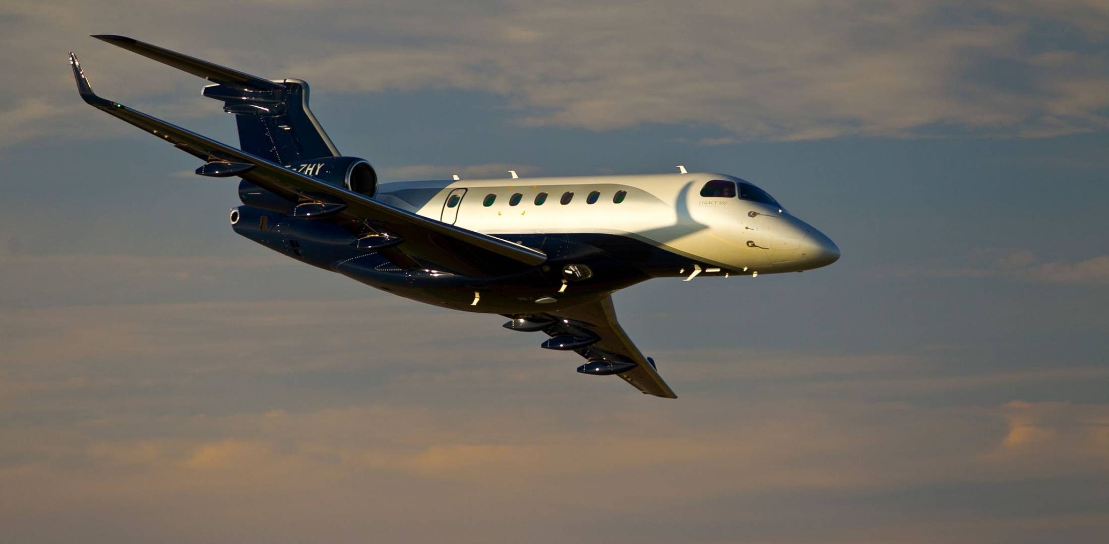 The Embraer Legacy 500 is a midsize business jet designed and manufactured by Embraer, a Brazilian aerospace company. It can accommodate up to 12 passengers and two crew members and has a range of up to 3,125 nautical miles (5,788 km).     The Legacy 500 features a spacious and modern cabin, with a flat floor and a generous baggage compartment. The cabin can be configured with various seating options, including a three-zone configuration with a divan, a club seating arrangement, or a conference table.      The cabin also features large windows, an advanced in-flight entertainment system, and a full galley.     The aircraft is equipped with two Honeywell HTF7500E turbofan engines, which provide 6,540 pounds of thrust each. The engines are designed to be fuel-efficient and produce lower emissions, while also providing the aircraft with excellent performance capabilities.     The cockpit of the Legacy 500 is equipped with the latest avionics and technology, including the Rockwell Collins Pro Line Fusion flight deck, which features large displays and intuitive touch-screen controls. The aircraft also features advanced safety systems, including fly-by-wire technology and an advanced flight management system.     Embraer has since introduced an updated version of the Legacy 500, called the Legacy 500E, which features enhanced performance, updated avionics, and a redesigned cabin.