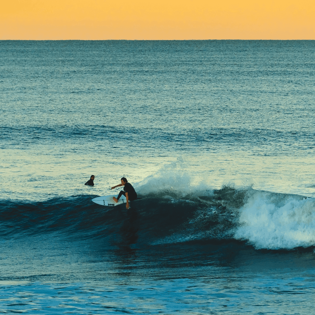 Surfer riding a wave at sunset – surfboard rental in jupiter