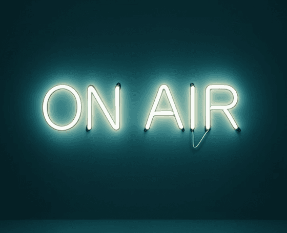 Neon sign reading "ON AIR" glowing brightly against a dark background, conveying a lively and professional broadcasting atmosphere.