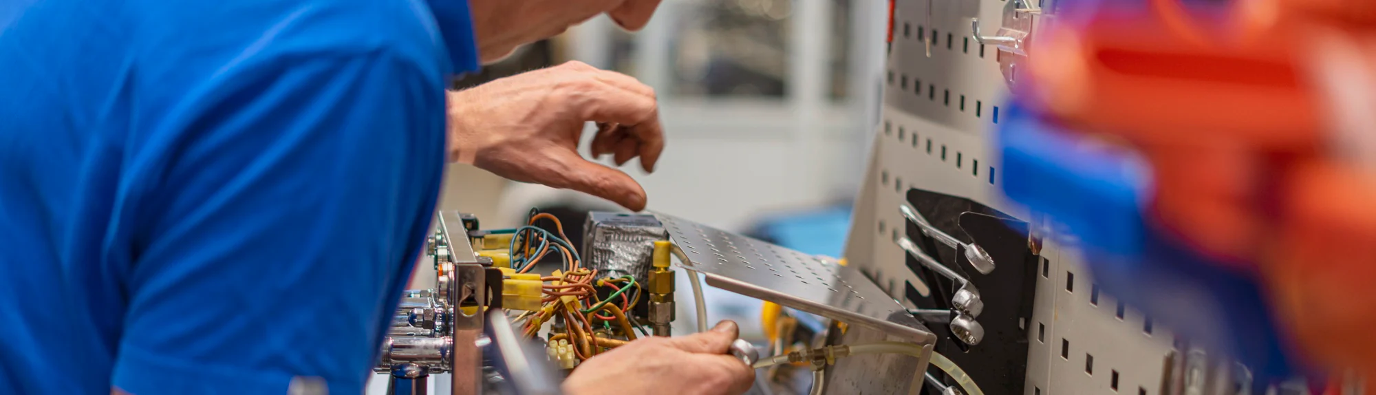 Een monteur met veiligheidskleding is hier een elektrakast aan het doormeten