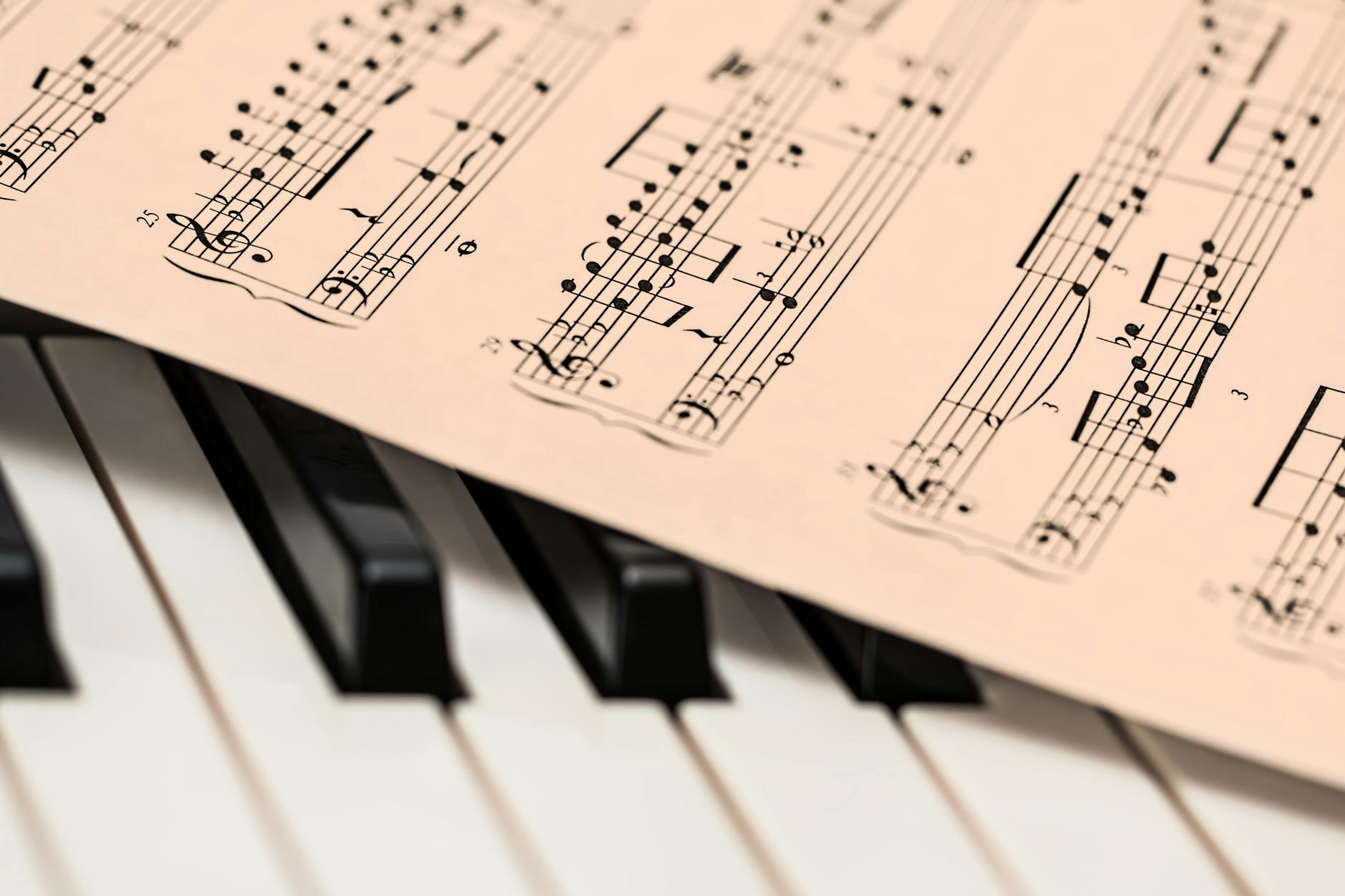 An open textbook on vocal pedagogy resting on a desk next to a tablet showing a waveform of a singing voice.