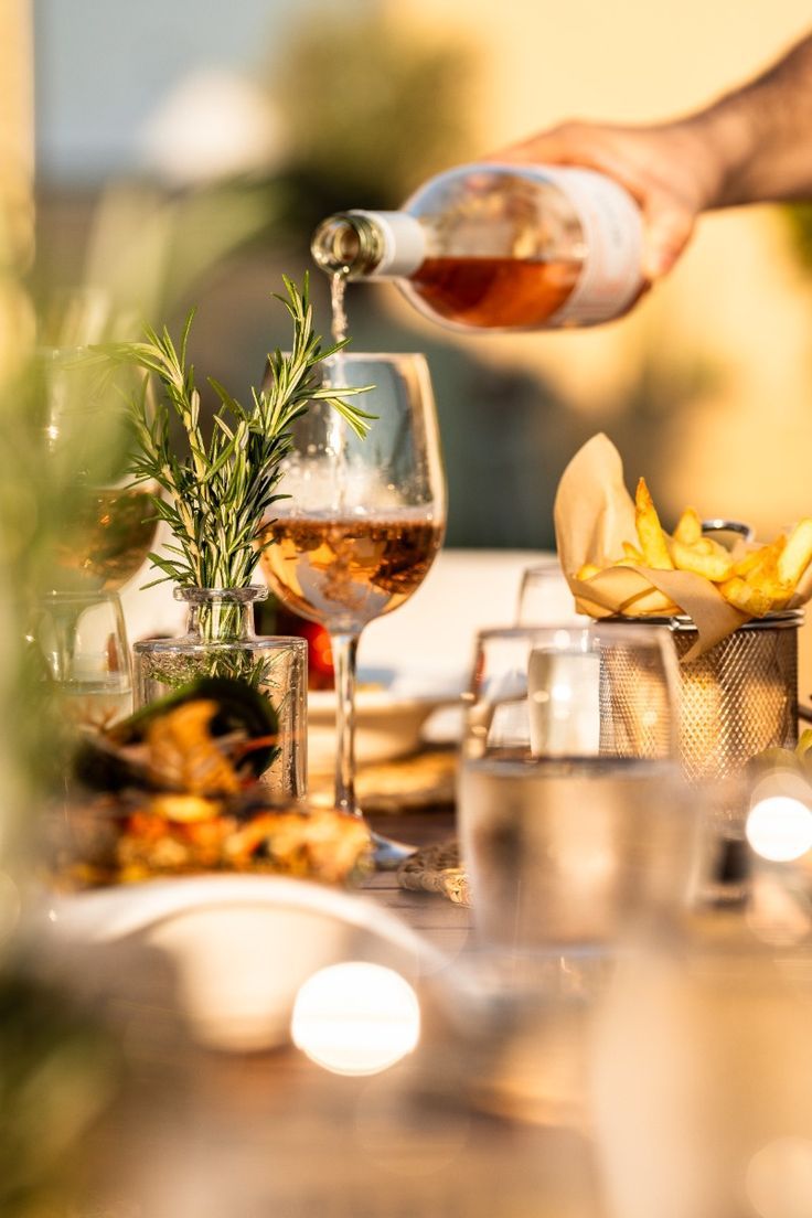 Une main remplie un verre de rosé pendant un brunch