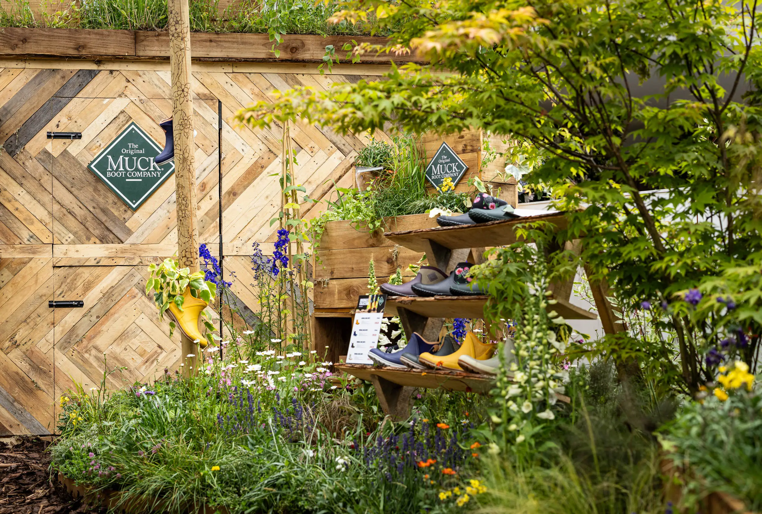 A garden scene with lush greenery surrounding a rustic building under bright sunlight.