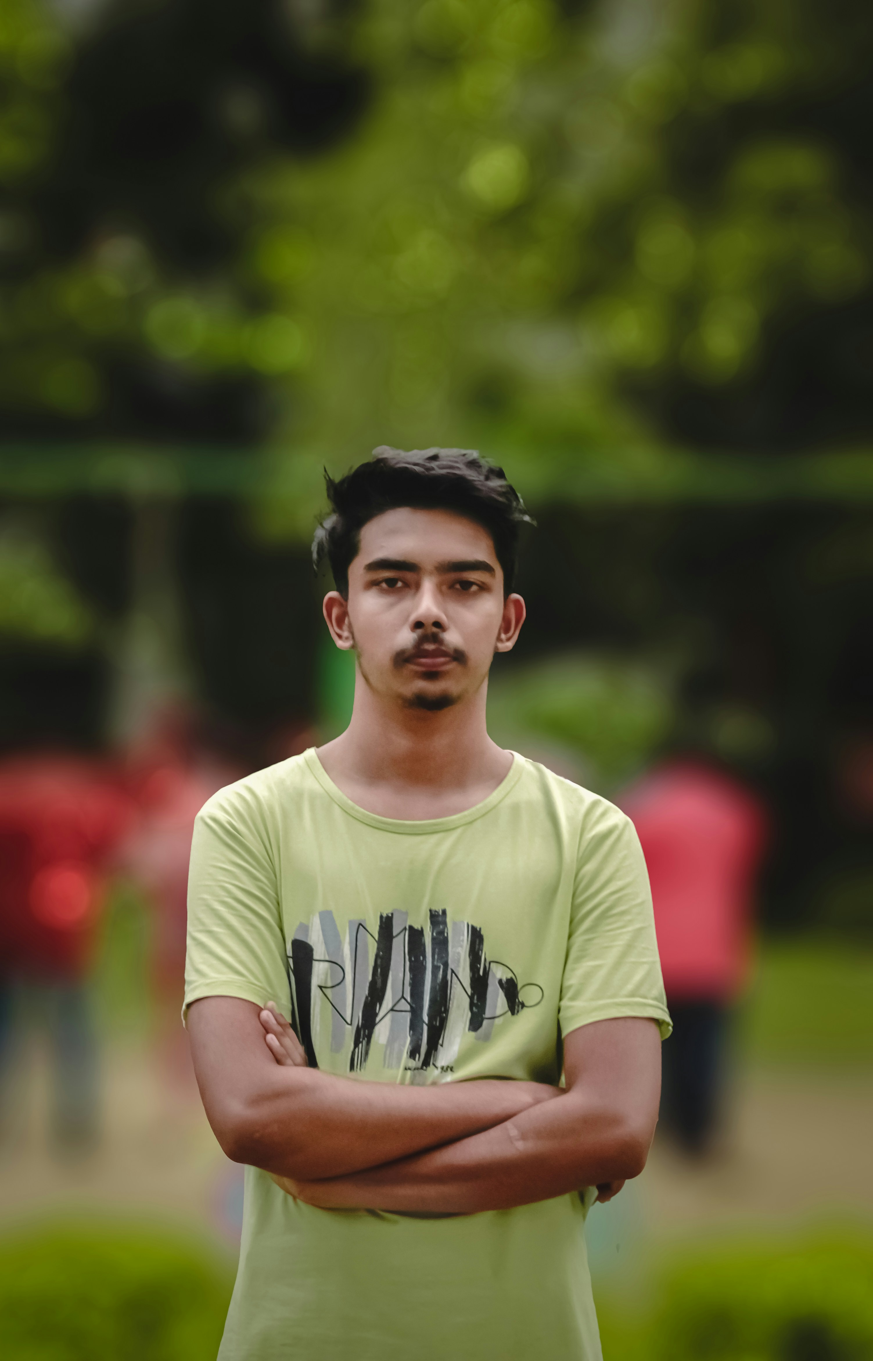 a man standing with his arms crossed in a park