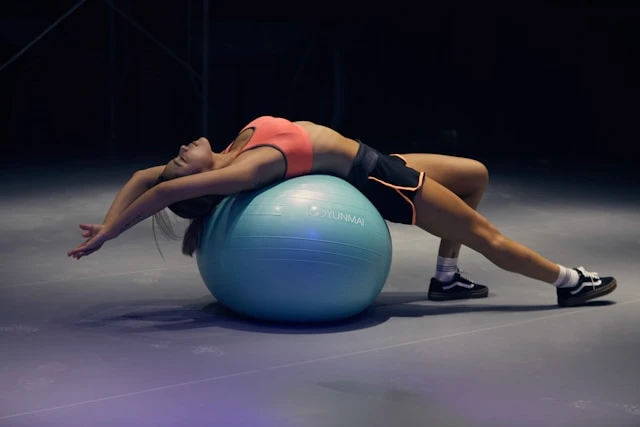 Woman lying on an exercise ball during a fitness session, taking a moment to rest