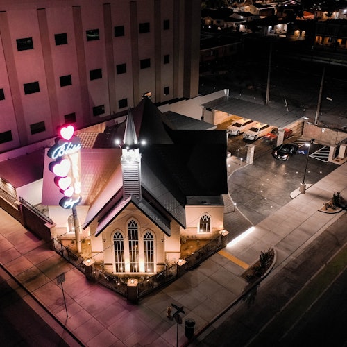 从空中俯瞰,一座建筑物的彩色玻璃窗、带有爱心和文本的发光标志,以及四周的街道在夜晚的景色。