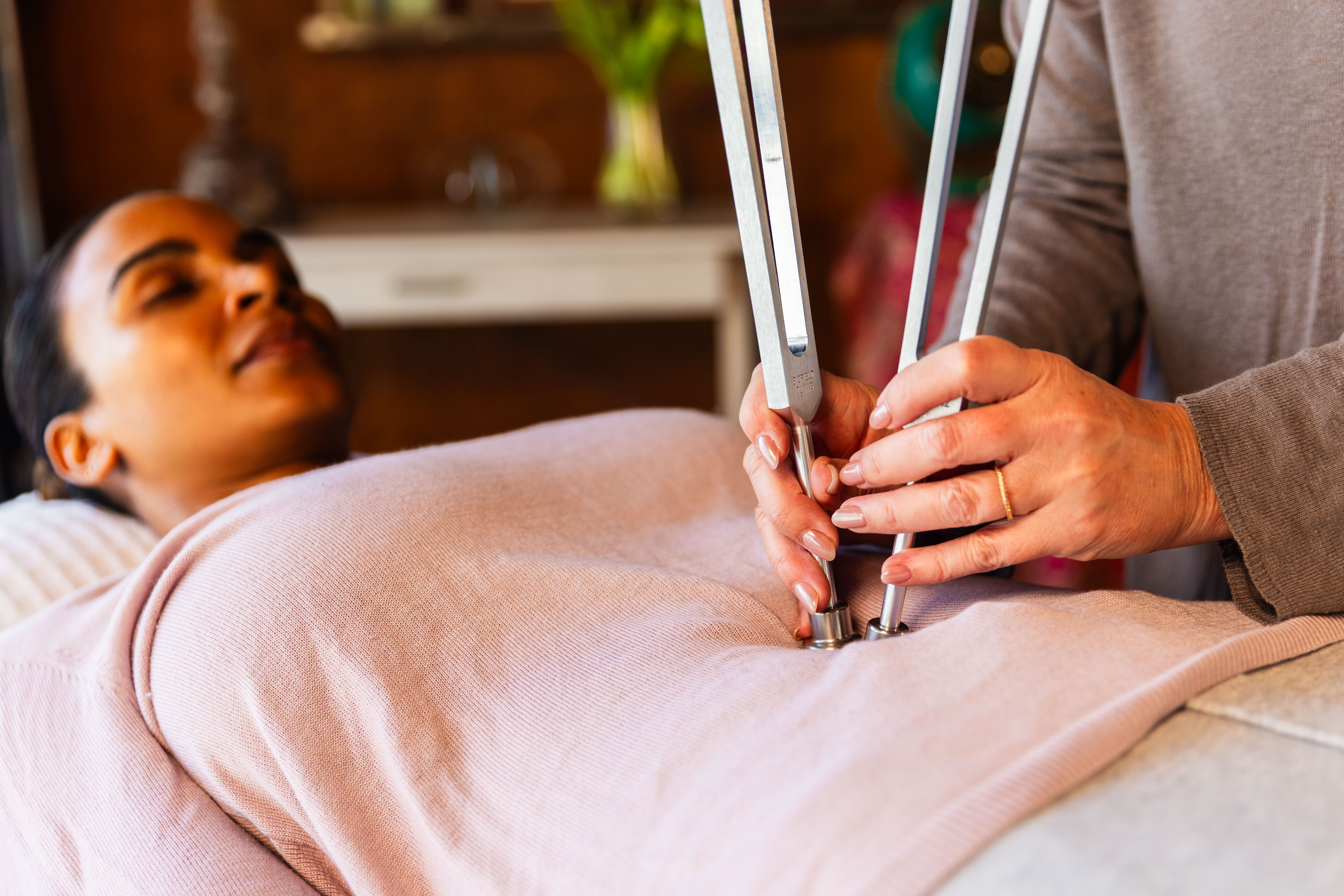 A woman lying down with a towel wrapped around her head, her face glistening with facial oil. Her eyes are closed, and she appears to be enjoying a spa treatment in a peaceful setting.