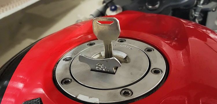 close-up picture of a key inserted into a gas cap of a red motorcycle